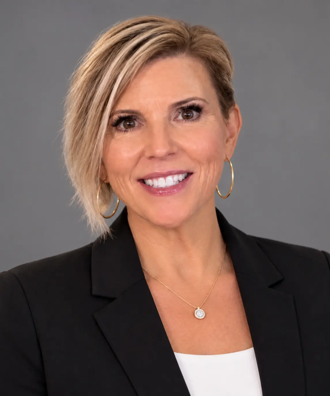 Smiling woman in black blazer against gray background