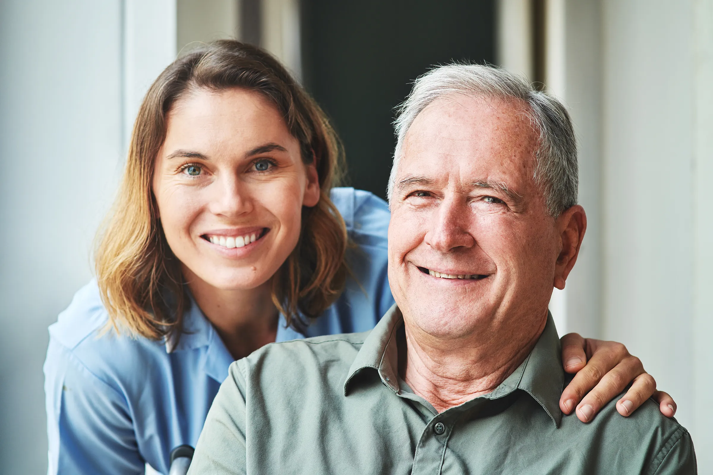 Smiling nurse with elderly man indoors