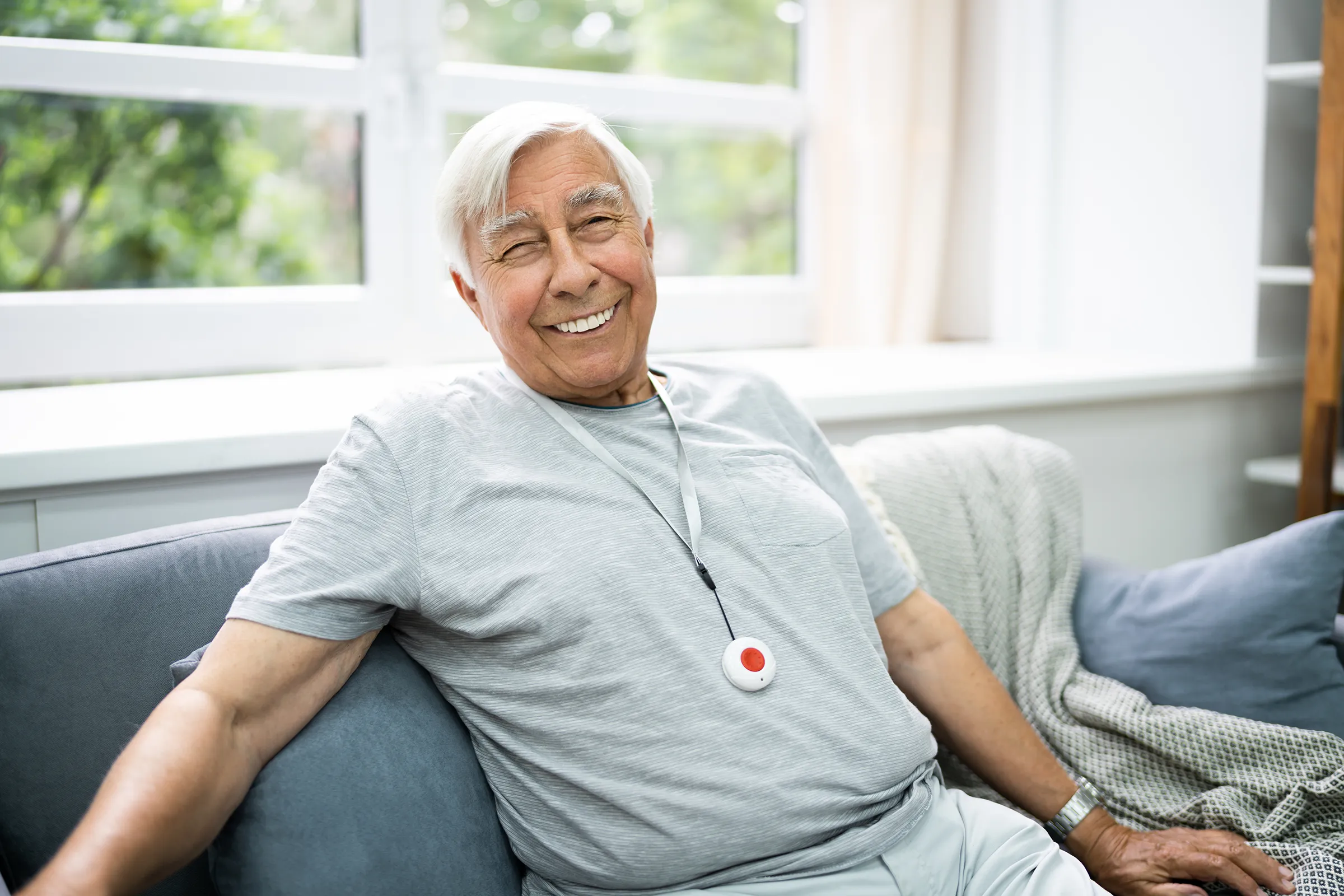 Smiling senior man wearing medical alert pendant at home