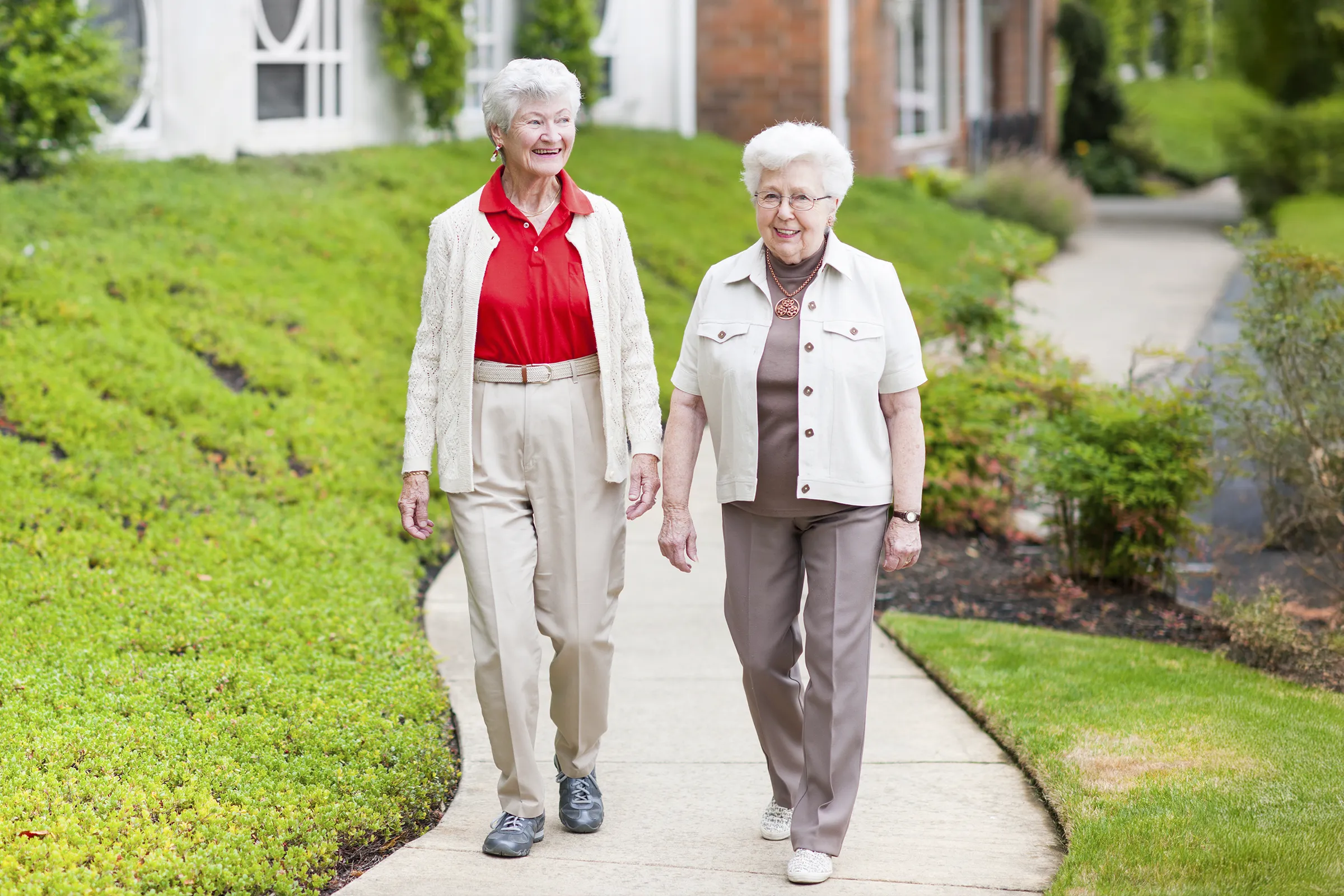 Two senior women walking on neighborhood sidewalk
